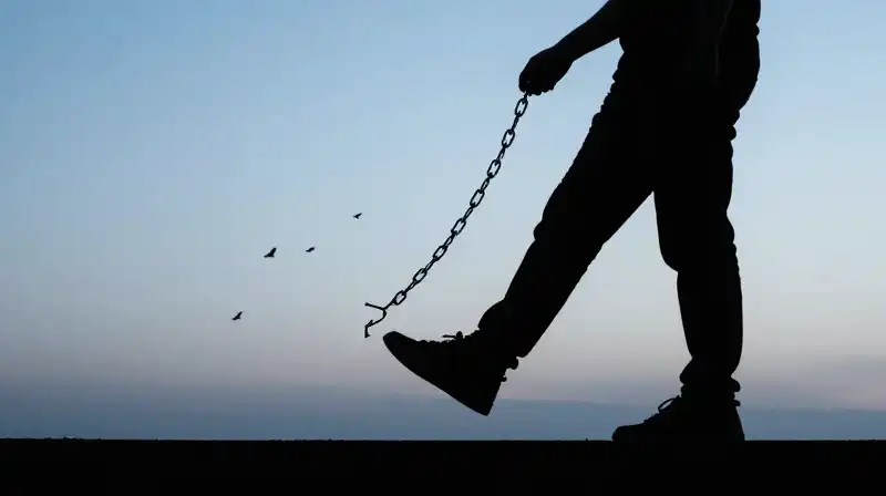 A silhouette steps into light as broken chains become birds