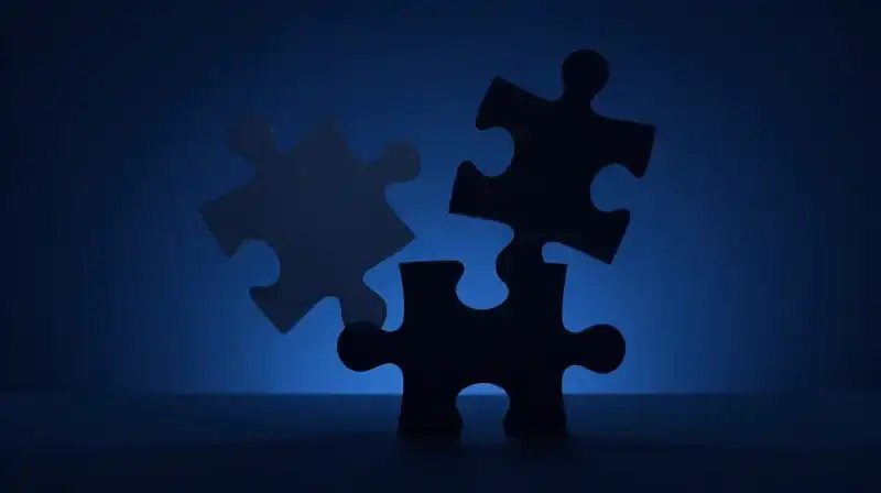 A fragmented silhouette balances intricate puzzle pieces in deep blue