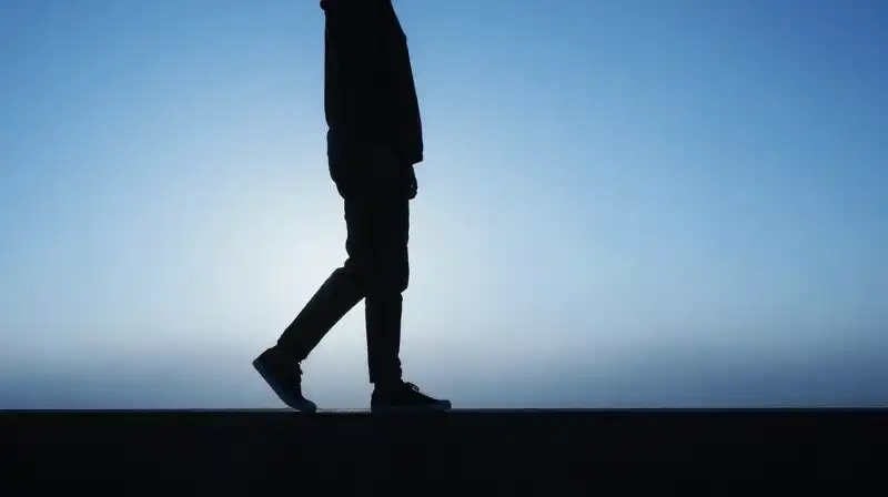 A silhouette steps from shadow toward a glowing blue horizon