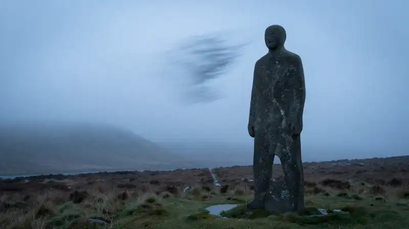 A lone silhouette stands firm against a misty highland gale