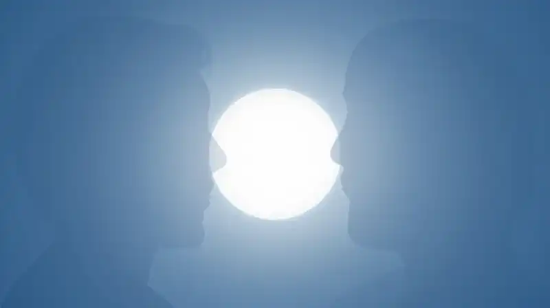 Two translucent silhouettes overlap near a glowing orb of light