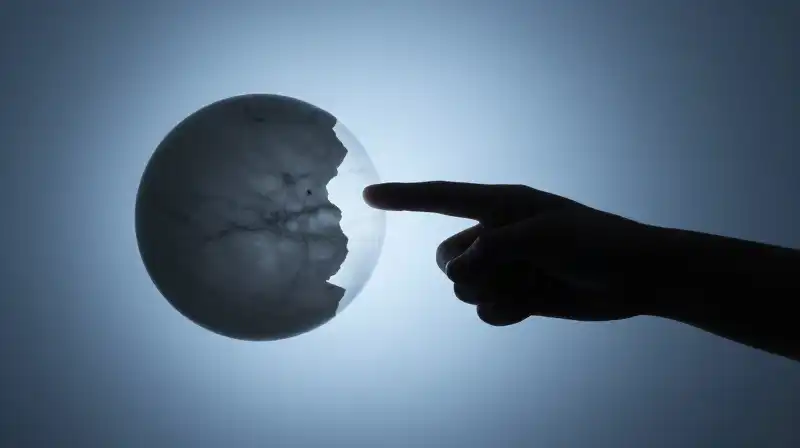 A fragmented silhouette points a finger amidst split marble spheres