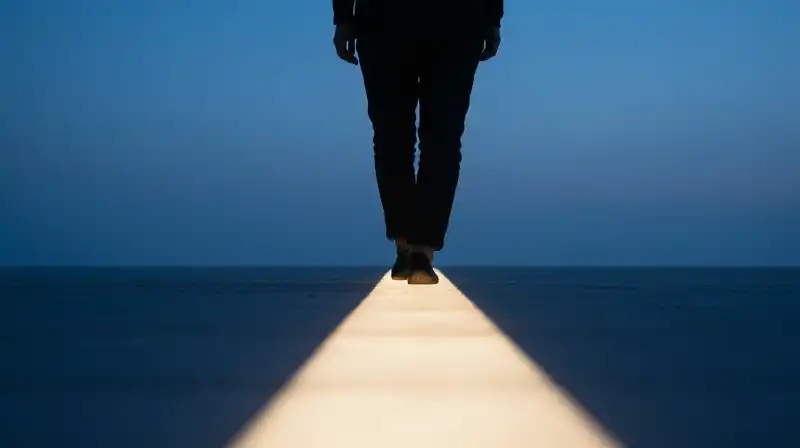 A silhouette walks toward a glowing horizon in deep blue