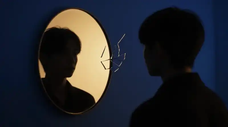 Two silhouettes face a glowing mirror and shattered glass