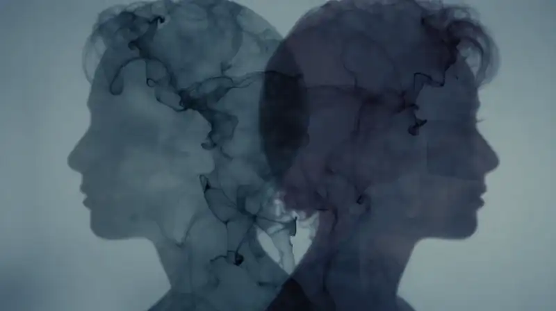 Two overlapping translucent silhouettes merge amidst flowing blue ink