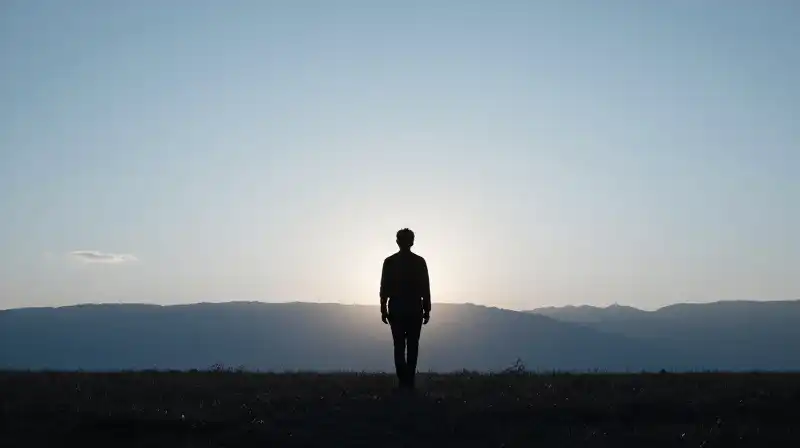 A silhouette walks toward a soft, glowing blue horizon