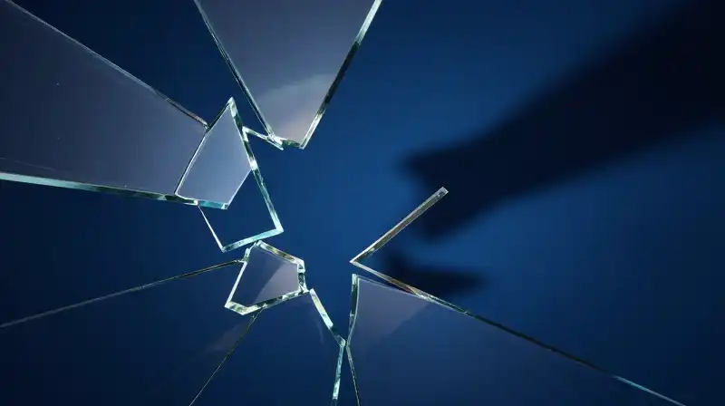 Fractured glass shards float amidst dissolving shapes in deep blue