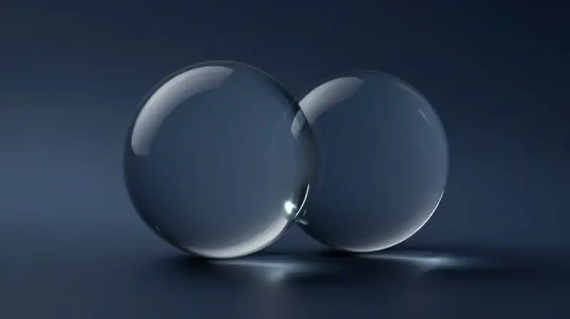 Two translucent glass spheres intersect over a dark blue background