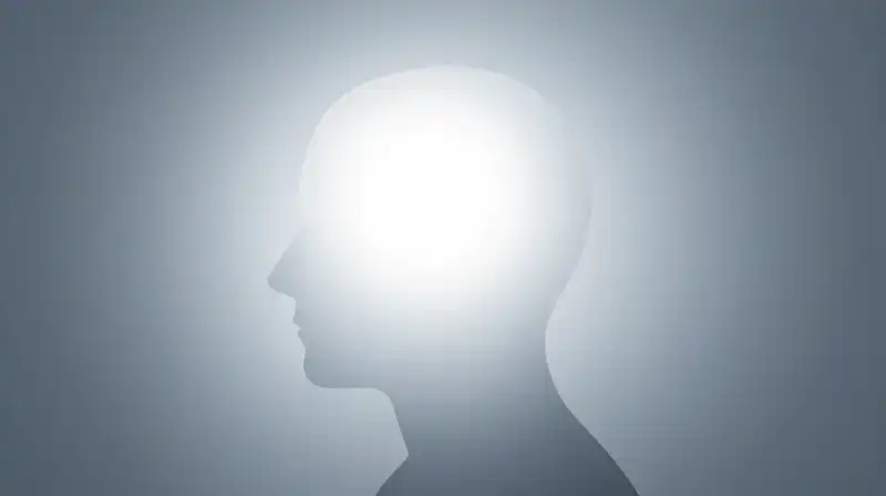A luminous white human head silhouette fades into blue shadows