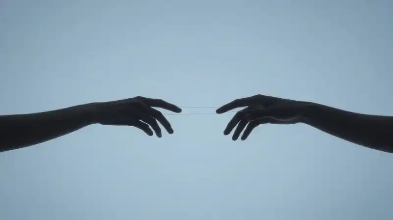 Two translucent silhouettes connect hands in a vast blue void