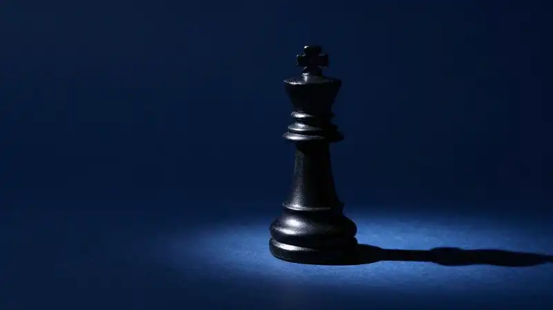 A polished obsidian chess piece stands in a dark void