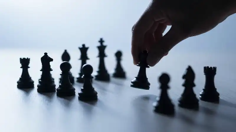 A hand moves a human silhouette chess piece across emptiness